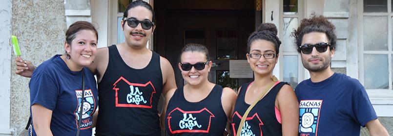 Five students wearing La Casa shirts standing on stairs leading to La Casa.
