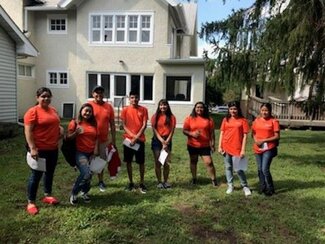 Group of eight Conéctate participants in orange shirts standing outside of La Casa