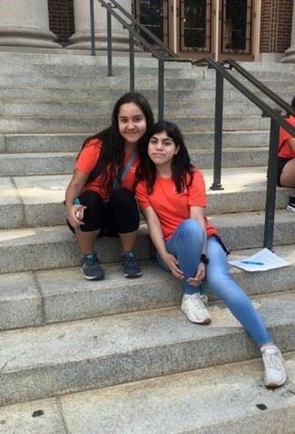 Two women in orange shirts seated on Foellinger Auditorium steps