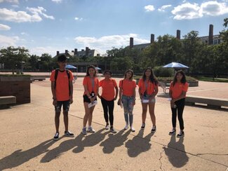 Six Conéctate participants in orange shirts standing outside on campus