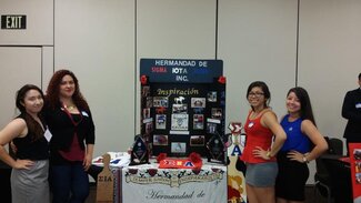 Four sorority members standing on either side of their chapter display board and info table