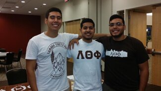 Three fraternity members in their chapter apparel with arms around each other