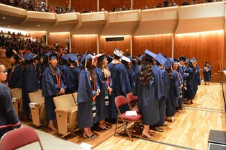 Rows of students wearing graduation robes and attire at the Krannert Center for the Performing Arts