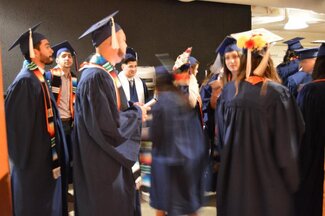 Group of students talking and wearing graduation robes and attire