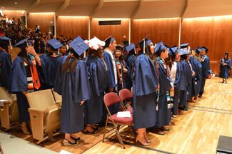 Rows of students wearing graduation robes and attire at the Krannert Center for the Performing Arts