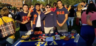 Four students from a fraternity working at an information table