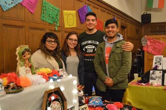 Four students posing with decorations in background and on table in front of them