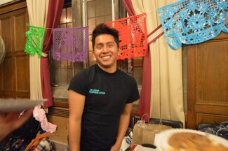 A male La Casa student employee smiling with decorations in background and table of food items nearby