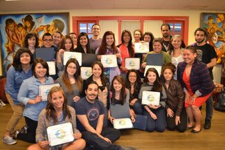 Large group of attendees smiling with many holding certificates in La Casa room