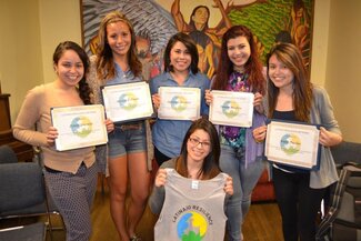Five women standing in back row holding certificates and one woman kneeling in front holding shirt with Latina/o Resiliency logo